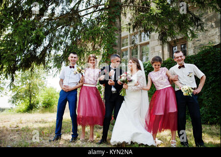 Bridesmaids with groomsmen and wedding couple jumping, dancing and having fun next to an old building. Stock Photo