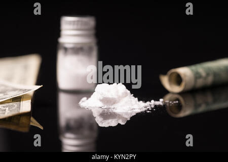 cocaine or other illegal drugs that are sniffed by means of a tube, isolated on black glossy background Stock Photo