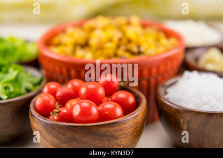 Tiny Cherry Tomatoes in Wooden Bowl with other mexican food ingredients Stock Photo