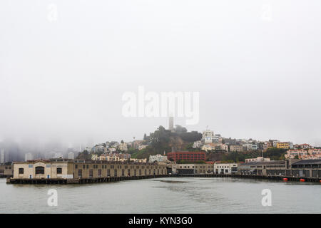 View of Pier 33 and city skyline, terminal for Alcatraz Ferry tours, and Pier 35 on a typically foggy day in San Francisco, California, USA Stock Photo