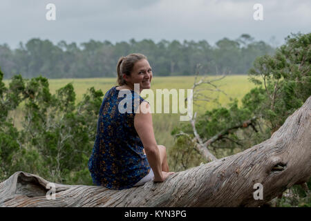 Woman Smiles Back at Camera from tree trunk perch Stock Photo