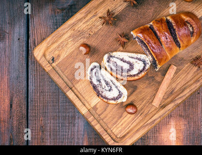 baked roll with poppy seeds on a wooden board, top view, empty space on the left Stock Photo