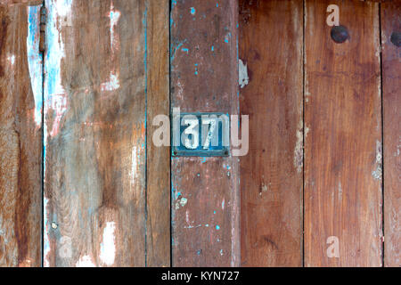 Old metal number 37 plaque on a old wooden door. Stock Photo