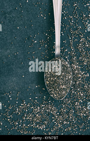 Salvia Hispanica seed. Chia seeds on and around a tea spoon on a slate background from above. Stock Photo