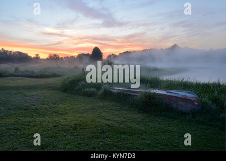 Fishing boat with fishermen gear lies on the banks of the river in the early morning fog Stock Photo