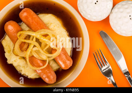 Scandinavian or Norwegian Sausage and Mashed Potatoes With Gravy and Fried Onions Against An Orange Backgroound Stock Photo