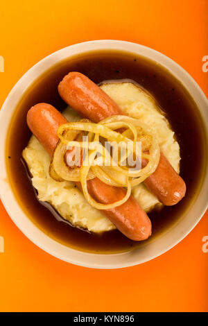 Scandinavian or Norwegian Sausage and Mashed Potatoes With Gravy and Fried Onions Against An Orange Backgroound Stock Photo