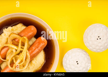 Scandinavian or Norwegian Sausage and Mashed Potatoes With Gravy and Fried Onions Against a Yellow Background Stock Photo