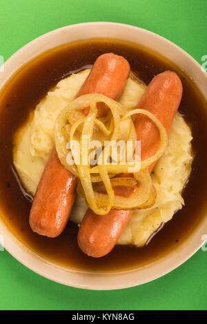 Scandinavian or Norwegian Sausage and Mashed Potatoes With Gravy and Fried Onions Against a Green Background Stock Photo