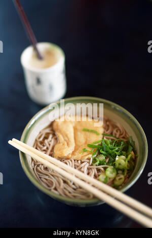 Bowl of Ramen with Soba noodles and tofu and Amazake drink on a table in a Japanese restaurant, Kyoto, Japan. Stock Photo