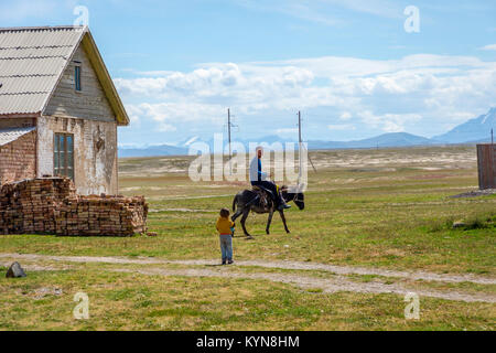 KEL-SUU, KYRGYZSTAN - AUGUST 13: Guy riding a donkey in a remote village in Kyrgyzstan. August 2016 Stock Photo