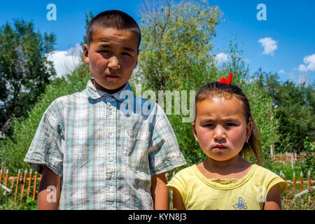 UGUT, KYRGYZSTAN - AUGUST 16: Siblings, brother and a sister posing with serious facial expression. Ugut is a remote village in Kyrgyzstan. August 201 Stock Photo