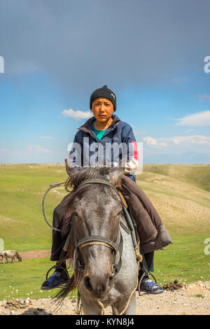 KAZARMAN, KYRGYZSTAN - AUGUST 14: Local guy wearing a hat sitting on a horse in remote Kyrgyzstan. August 2016 Stock Photo