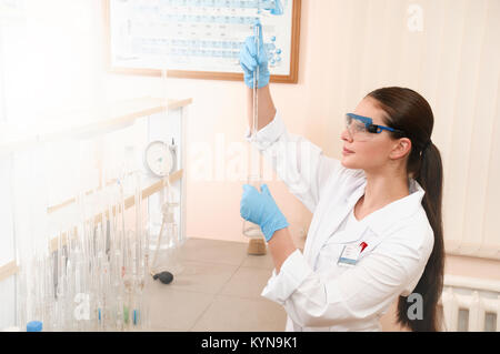 Focused young sciencist pipetting solution into the glass cuvette. Healthcare and biotechnology concept. Stock Photo