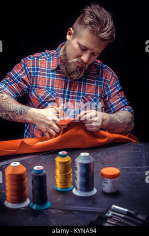 Artisan cutting out leather goods in his workshop Stock Photo