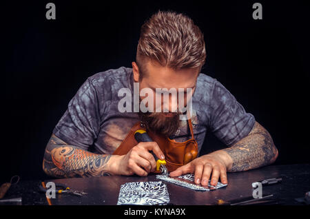 Leather master works with leatherwork in his work area Stock Photo