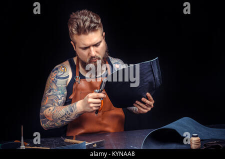 Worker of leather cuts out leather goods Stock Photo