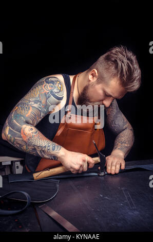 Craftsman working with leather cutting leather outlines for his new production Stock Photo