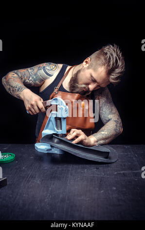 Leather Craftsman performs leather working for a new product in the work area Stock Photo