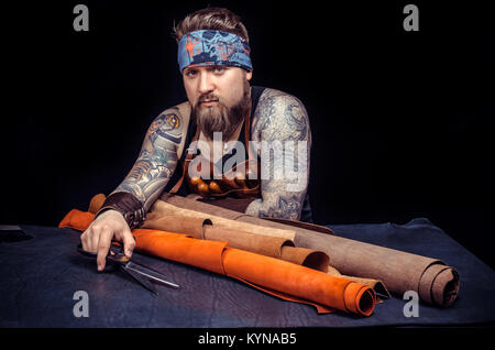 Craftsman demonstrates leather cutting process at the shop Stock Photo