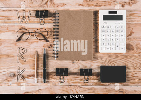 top view of calculator with eyeglasses and office supplies on wooden tabletop
