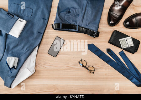 top view of suit and accessories with smartphone on wooden tabletop Stock Photo