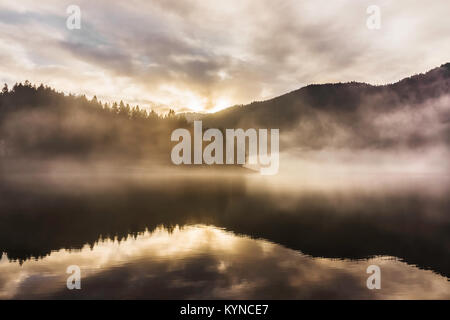 Sunset on the Kruth-Wildenstein Lake during a misty day of winter, Vosges, France. Stock Photo