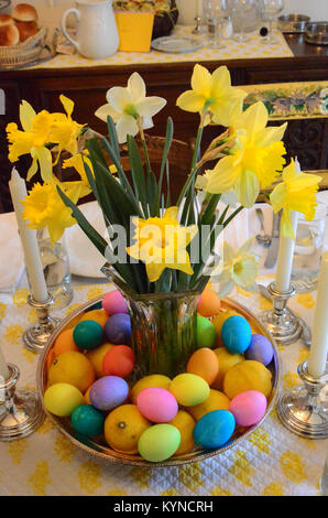 Daffodils and colored eggs - traditional symbols of spring - decorate a dining table at Easter. Stock Photo
