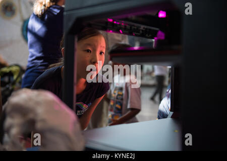 At the Steven F. Udvar-Hazy Center, a visitor observes a rocket model being printed using a Makerbot 3D printer. The event, supported by NASA and ASME, demonstrates 3D printing applications in aerospace engineering, technology, and STEM education programs. Stock Photo
