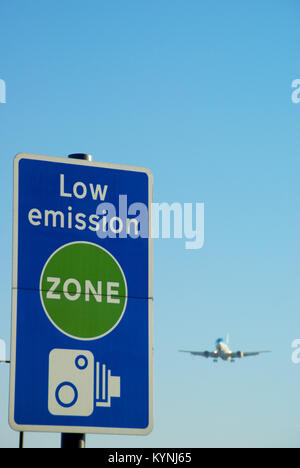 Low emission zone sign with jet plane landing at London Heathrow Airport. Air pollution. Carbon dioxide emissions. Aviation Stock Photo