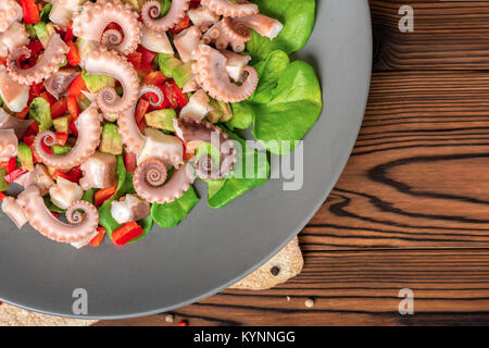 salad with tentacles of octopus, lime, avocado, red peppers and lettuce, restaurant food, copy space Stock Photo