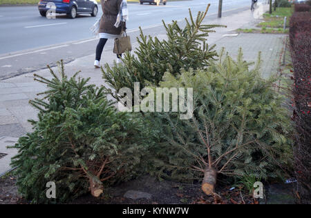 Berlin, Germany. 15th Jan, 2018. People pass by abandoned christmas trees that have been placed on pedestrian walkways in Berlin, Germany, 15 January 2018. The Berlin city cleaning department will collect unwanted christmas trees for free in the upcoming days. Credit: Wolfgang Kumm/dpa/Alamy Live News Stock Photo