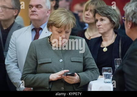 Trinwillershagen, Germany. 12th Jan, 2018. German Chancellor Angela Merkel (CDU) checks her telephone during the New Year's Reception of the state counsil of the district Vorpommern-Ruegen in Trinwillershagen, Germany, 12 January 2018. Merkel has been representing the electoral district Stralsund-Greifswald-Ruegen-Vorpommern since 1990 in the German Bundestag with a direct mandate. Credit: Stefan Sauer/dpa/Alamy Live News Stock Photo