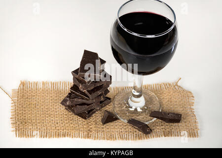 red wine in stemware with dark chocolate candy on brown burlap Stock Photo