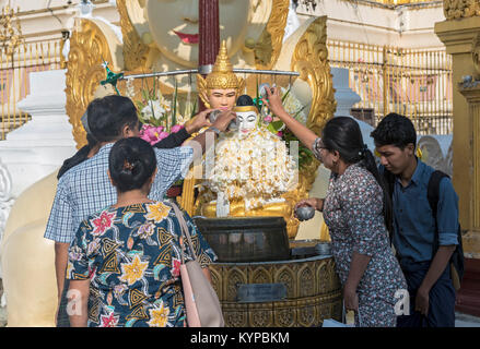 Worshippers pour water over Buddha statue, Shwedagon Pagoda, Yangon, Myanmar (Burma) Stock Photo