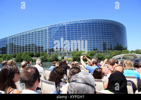 Tourists and holiday makers on a river boat trip around Strasbourg France view and photograph the European Parliament and court of human rights