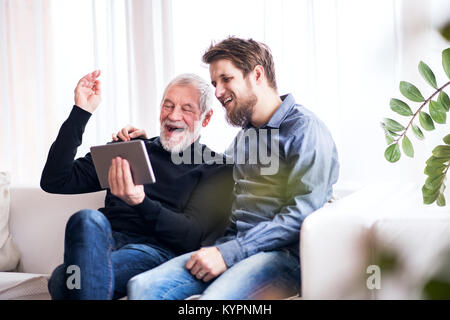 Hipster son and his senior father with tablet at home. Stock Photo