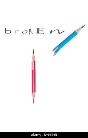 On the word broken indicates a double-edged pencil lying next to half a broken pencil, isolated on a white background Stock Photo
