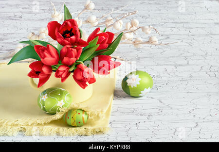 Red tulips with luight green Easter eggs on white cracked background with white paper flowers Stock Photo