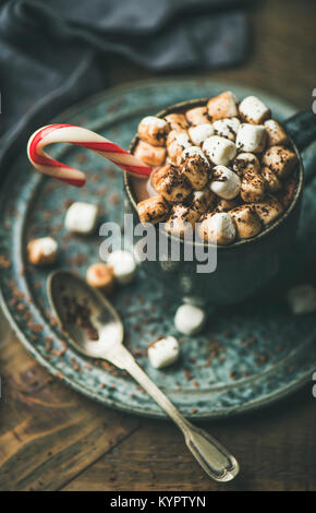 Winter warming sweet drink hot chocolate with marshmallows and cocoa in mug with Christmas holiday candy cane on wooden background, selective focus Stock Photo