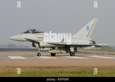 RAF Typhoon taxiing off the Coningsby runway after landing as another emerges from the mist behind. Stock Photo