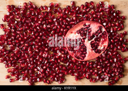 cross section of pomegranate and pomegranate seeds on wooden board Stock Photo