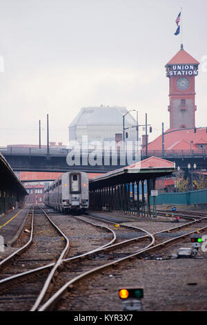Passenger train stands on the curved railroad at historic railway station with awnings in Portland Oregon in little foggy weather Stock Photo