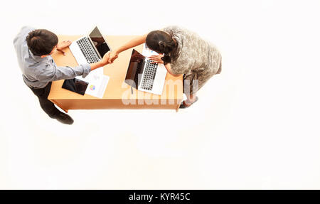 Top view of businessman and businesswoman standing and shaking hands over table in the meeting with copy space on isolated white background Stock Photo