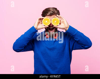 Man holding two half of orange in front of eyes Stock Photo