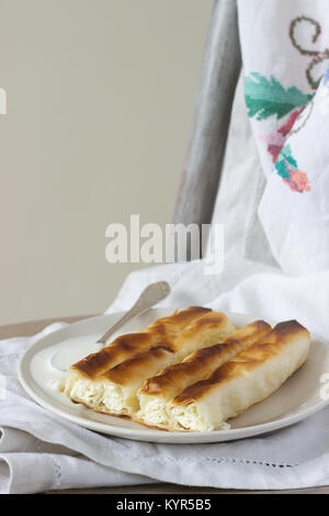 Vertuta or placinta with cottage cheese and cheese, served with sour cream. Traditional Moldovan, Romanian or Balkan pie or cake. Rustic style. Stock Photo