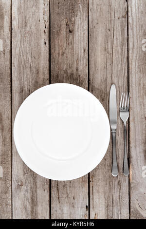 top view of arranged empty plate, fork and knife on wooden table Stock Photo