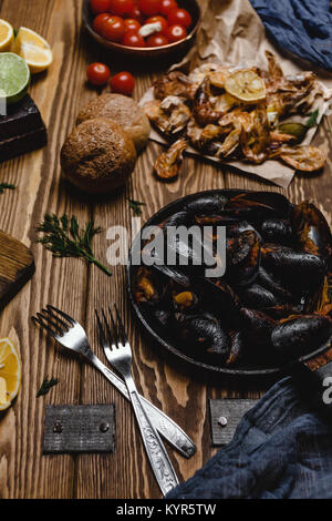 Assorted cooked seafood with bread and tomatoes on wooden table Stock Photo