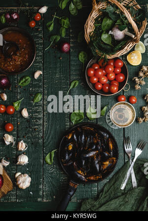 Top view of cooked mussels with shells served in pan with tomatoes, herbs and wine on wooden table Stock Photo