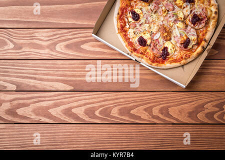 Pizza in cardboard box on wooden table Stock Photo